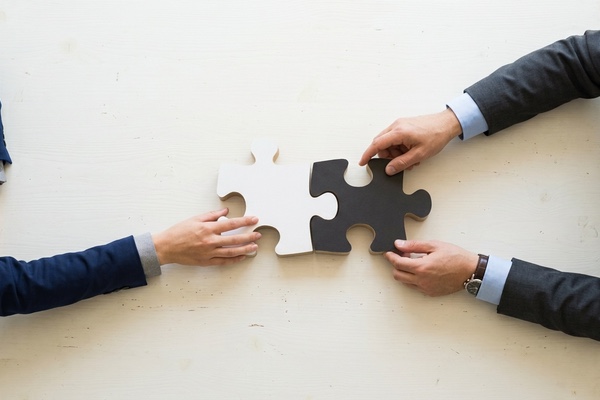 Two people fitting a pair of puzzle pieces together
